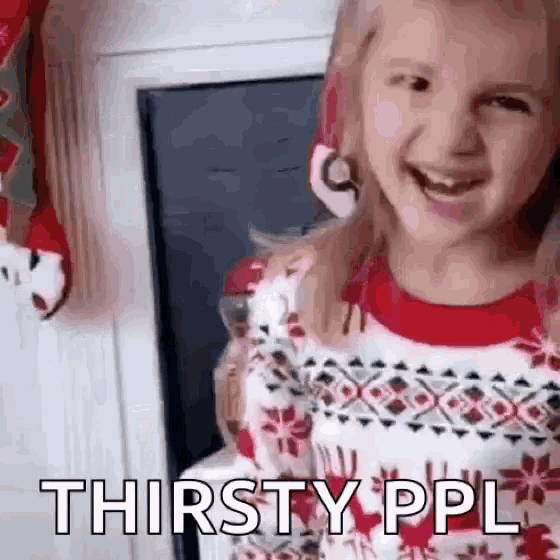 a little girl wearing a christmas sweater is smiling and saying thirsty ppl .