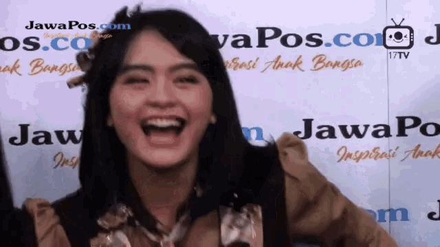 a woman laughs in front of a wall that says javapos.com