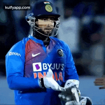 a cricket player wearing a helmet and a blue jersey is holding a bat .