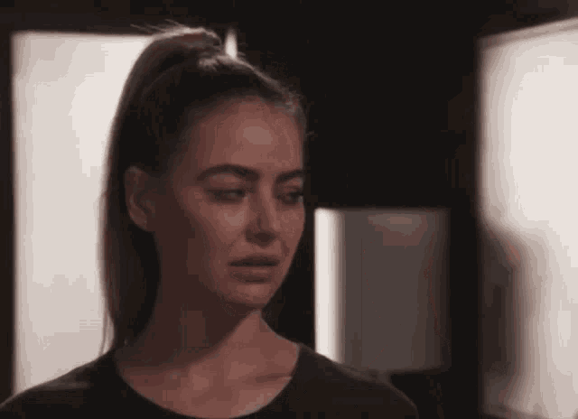 a woman with a ponytail and a black shirt looks sad