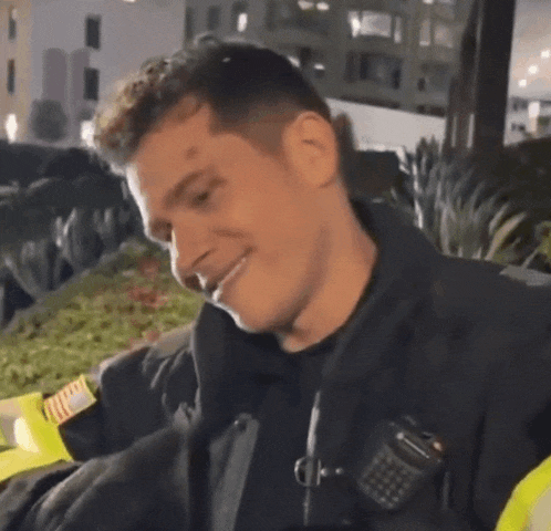 a police officer is smiling while talking on a walkie talkie