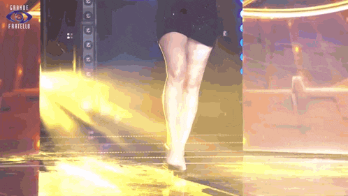 a woman in a short black dress is walking on a stage with the words grande fratello behind her