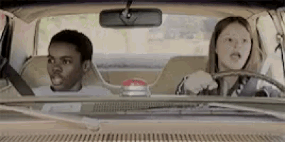a man and a woman are sitting in a car . the woman is driving and the man is sitting in the back seat .