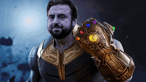 a man with a beard is holding a glove that says infinity gauntlet on it
