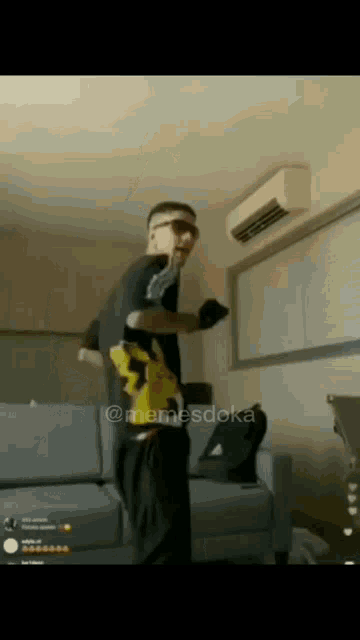 a man is dancing in a living room with a couch and air conditioner .