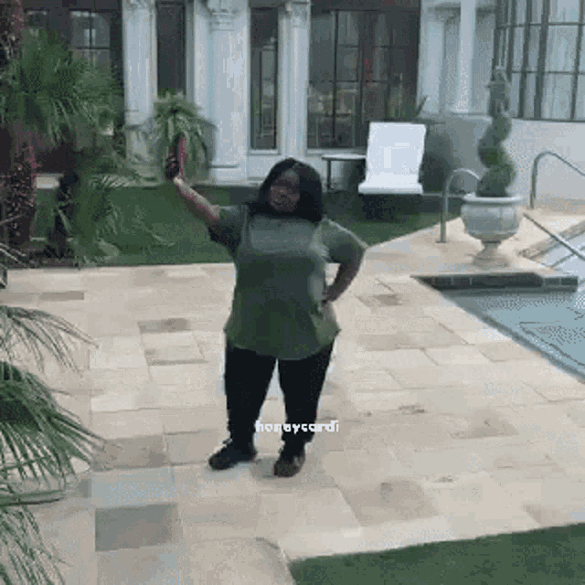 a woman is standing on a patio in front of a swimming pool .