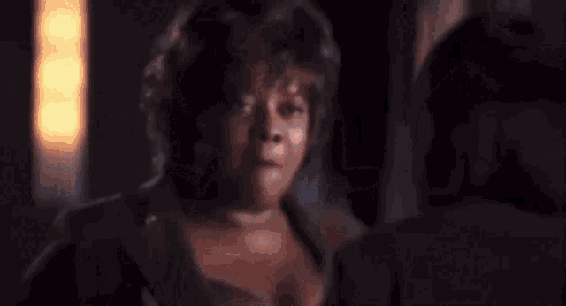 a woman is sitting in a dark room looking at her phone
