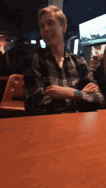 a man in a plaid shirt is sitting at a table
