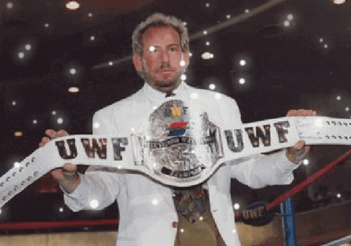 a man in a white suit is holding a belt that says uwf on it