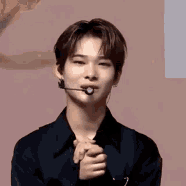 a young man wearing a microphone is making a funny face .