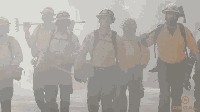 a group of firefighters are walking through a smokey area with a regal logo in the corner