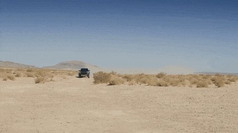 a truck with the letter c on the front is driving on a dirt road