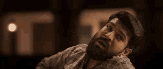 a man with a beard is screaming with his mouth open and his arm outstretched .