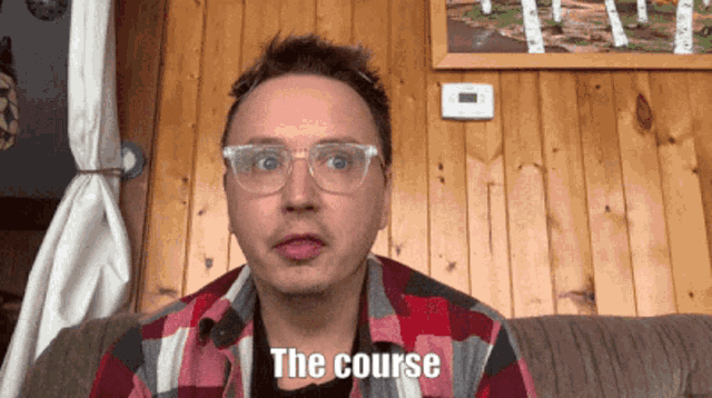 a man wearing glasses is sitting on a couch and says the course