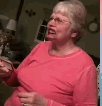 an elderly woman wearing glasses and a pink shirt is laughing