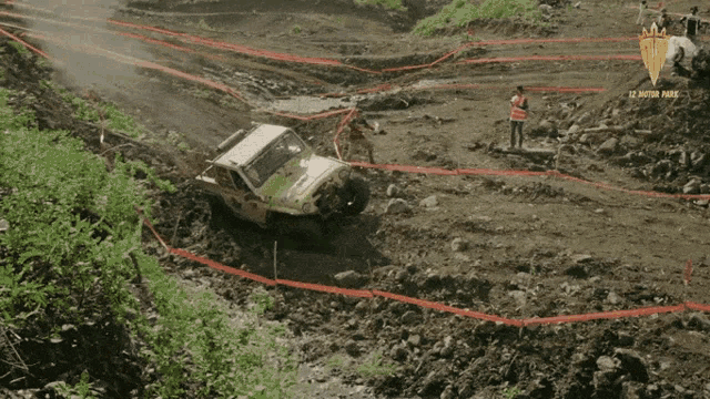 a jeep is going down a muddy hill with a sign that says 12 motor park