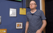 a man in a striped shirt is standing in front of a blue wall with pictures on it