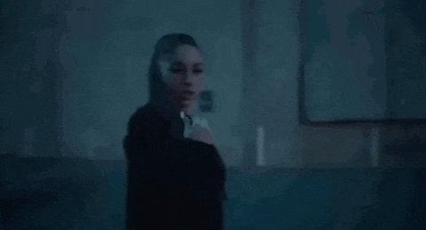 a woman in a ponytail is standing in a dark room .