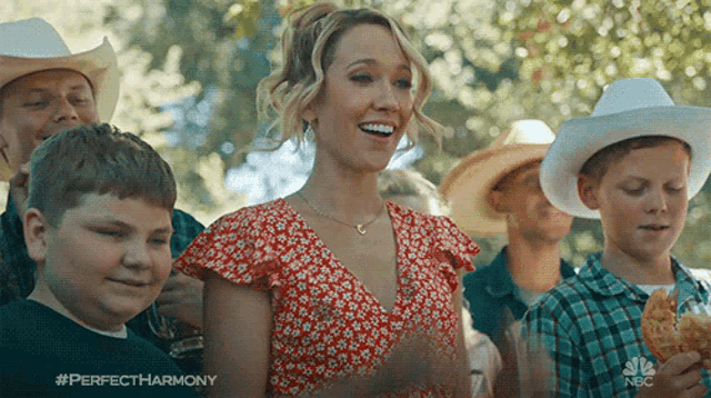 a woman in a red dress is surrounded by cowboy hats and boys