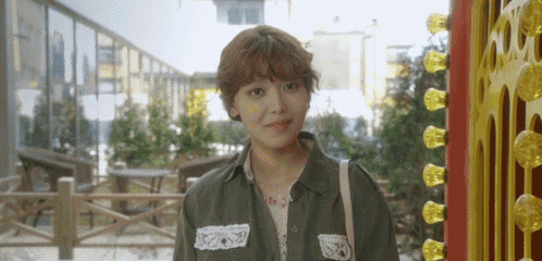 a woman with short hair is standing in front of a building and looking at the camera .