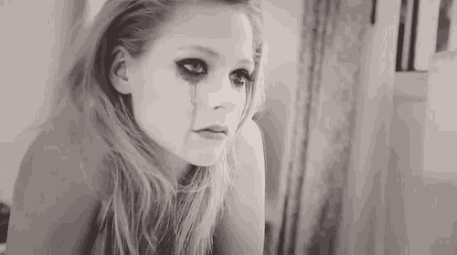 a woman is crying in front of a mirror and has a tear running down her face .
