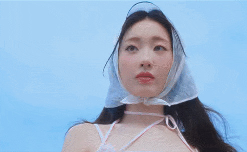 a woman wearing a clear plastic head scarf looks at the camera against a blue sky .