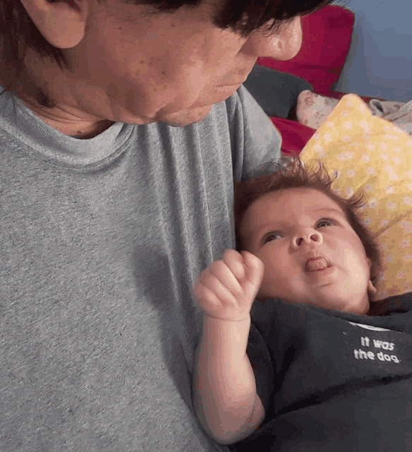 a man holds a baby whose shirt says it was the best