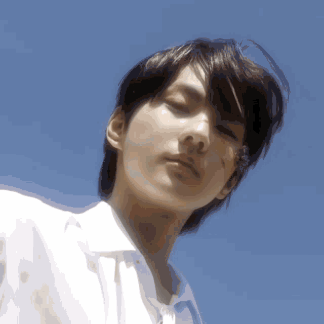 a close up of a young man 's face against a blue sky