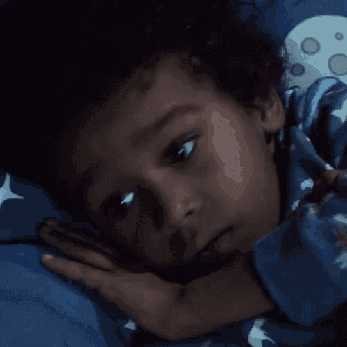 a young boy is sleeping in a bed with a blue blanket and a moon on it