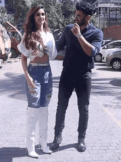 a man and a woman standing next to each other on a brick sidewalk .