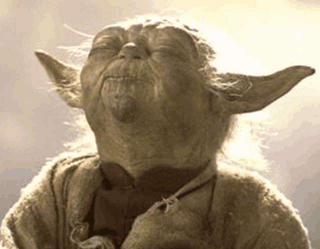 a close up of a statue of yoda from star wars with his eyes closed and his mouth open .