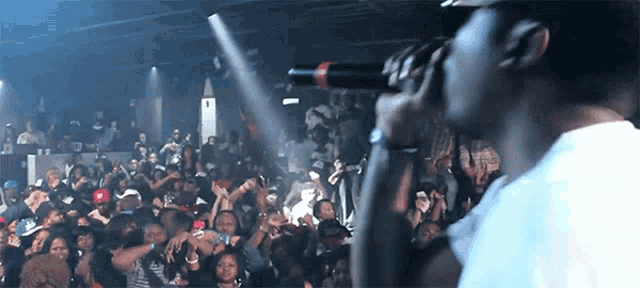 a man singing into a microphone in front of a crowd with the number 1 in the background