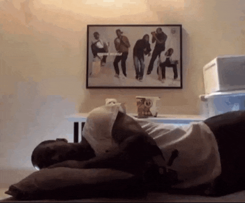 a man is laying on his stomach on a bed in front of a picture on the wall .