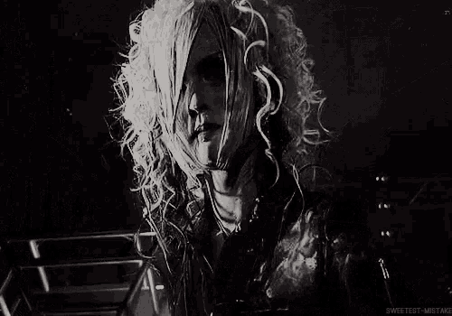 a black and white photo of a woman with white hair and piercings in her ears .