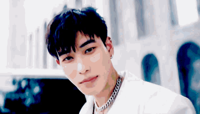 a young man wearing a white jacket and a chain around his neck