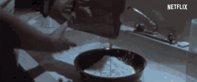 a person is pouring liquid into a bowl with a netflix logo in the background