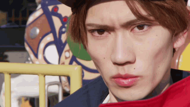 a close up of a young man 's face with a fence in the background
