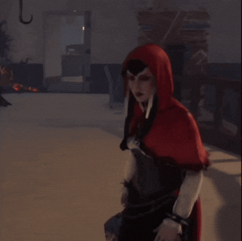 a woman in a red hooded cape points to something