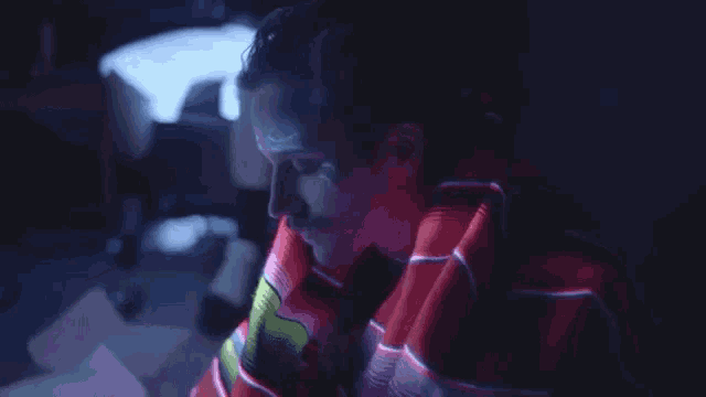 a man wrapped in a blanket is sitting in front of a computer screen in a dark room .