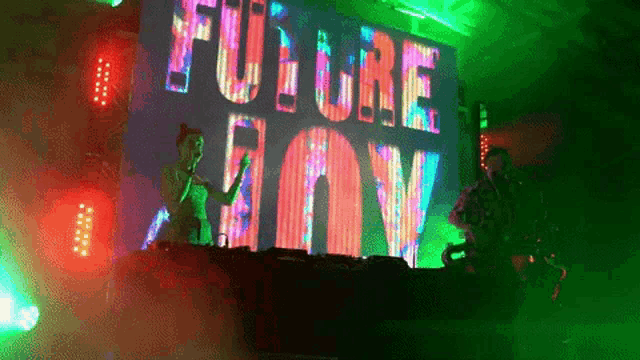 a woman singing in front of a large screen that says future joy