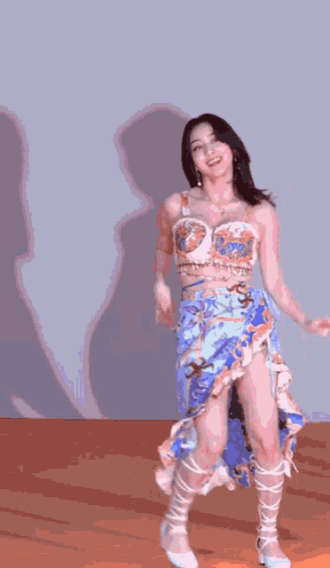 a woman in a blue skirt is dancing on a stage in front of a wall .