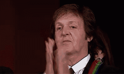 a man wearing a suit and tie is clapping his hands