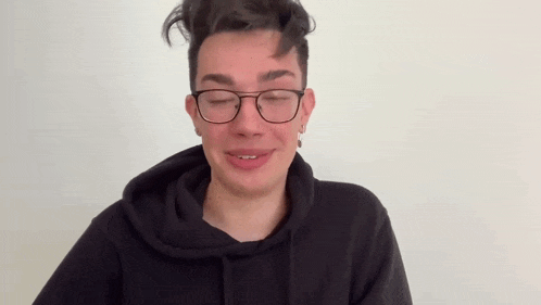 a young man wearing glasses and a hoodie is making a funny face .