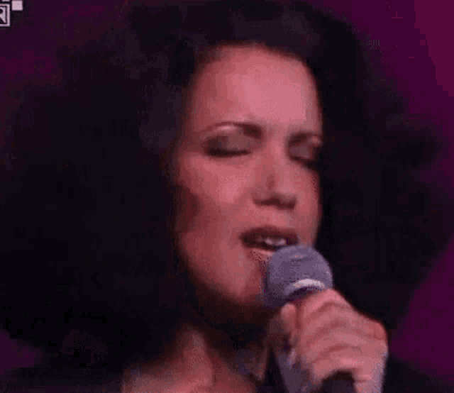 a pixelated image of a woman singing into a microphone with a purple background