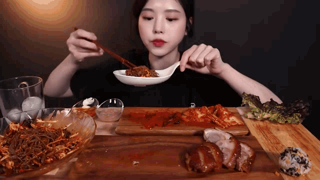 a woman is eating a meal with chopsticks and a spoon
