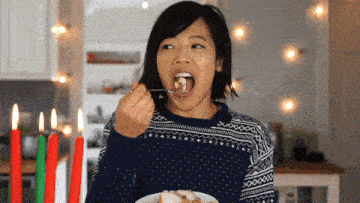 a woman in a sweater is eating a piece of food with a fork