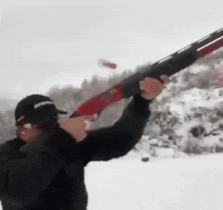 a man is holding a shotgun in the snow and shooting it