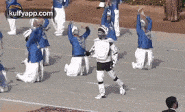a group of people in blue and white uniforms are performing a dance routine .