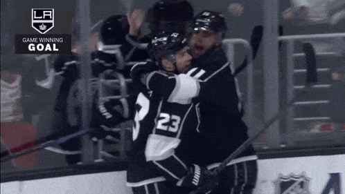 a hockey player with the number 23 on his jersey is hugging another hockey player