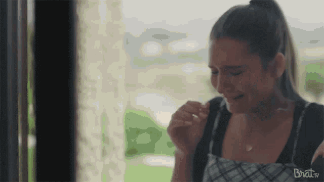 a woman is crying while standing in front of a window in a room .